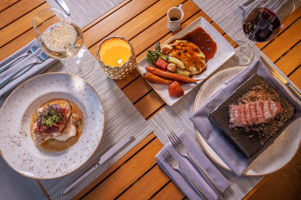 three different plates featuring menu items from Hualani's restaurant at Timbers Kaua'i
