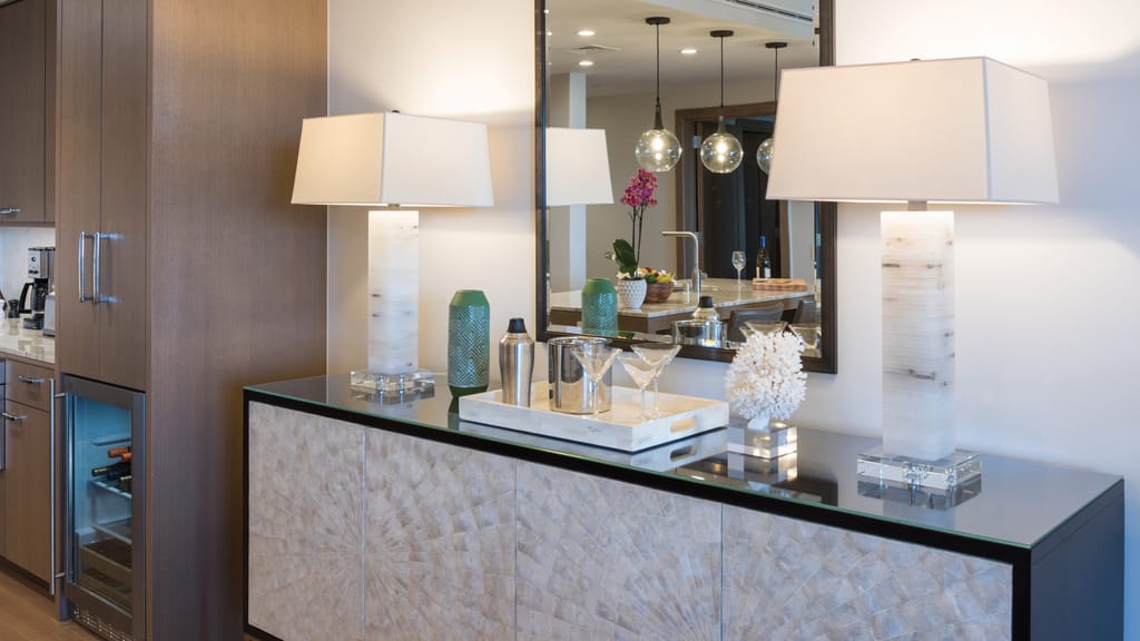 A stylish wet bar area with a wine fridge, cabinets, and decorative items.