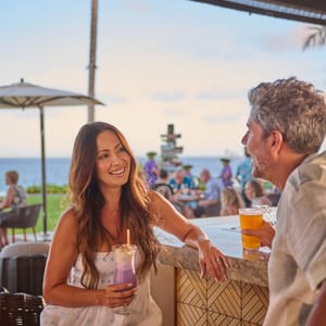 a couple enjoy a cocktail at the bar at Hualani's restaurant at Timbers Kaua'i