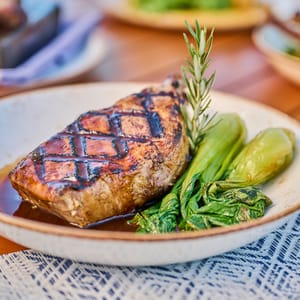 A perfectly seared steak with roasted vegetables and rosemary sprig on a plate