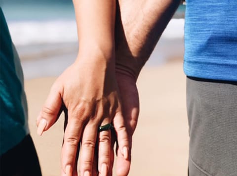 a closeup of two clasp hands on a beach