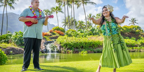 traditional polynesian entertainers perform; a man with a ukelele and a female hula dancer